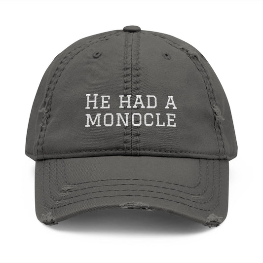 Gray cap with 'He Had a Monocle' text on a white background